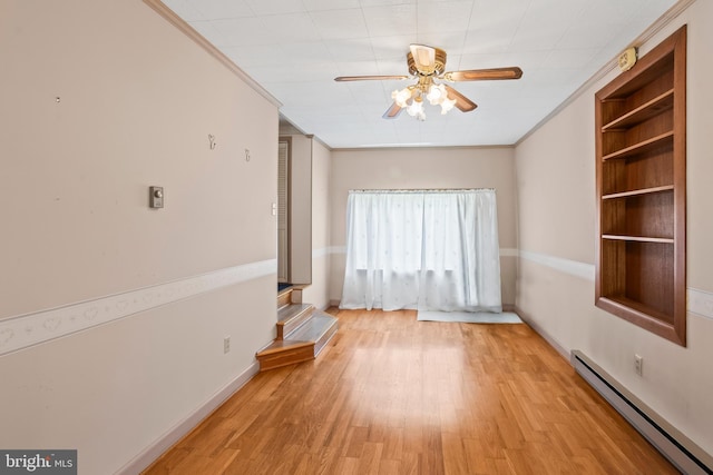 empty room with a baseboard heating unit, a ceiling fan, wood finished floors, baseboards, and ornamental molding