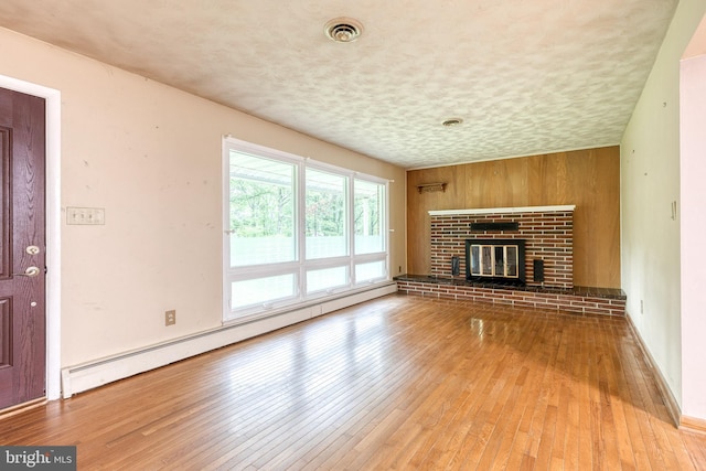 407 Stately Dr, Pasadena, MD 21122 - unfurnished living room with baseboard heating, light wood-style floors, a fireplace, and a textured ceiling