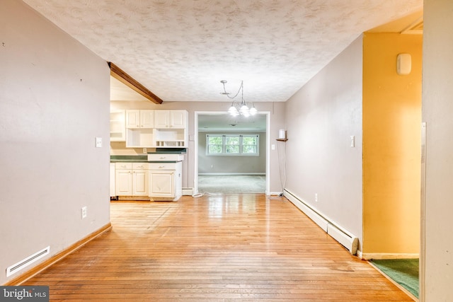 407 Stately Dr, Pasadena, MD 21122 - unfurnished dining area with a baseboard heating unit, light wood finished floors, a chandelier, a textured ceiling, and baseboards