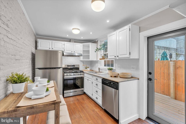 kitchen with a sink, white cabinetry, light wood-type flooring, under cabinet range hood, and appliances with stainless steel finishes