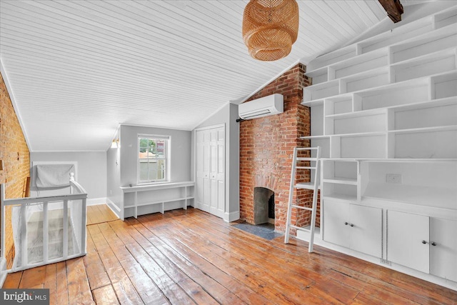 unfurnished living room featuring vaulted ceiling, a wall unit AC, wooden ceiling, baseboards, and hardwood / wood-style flooring