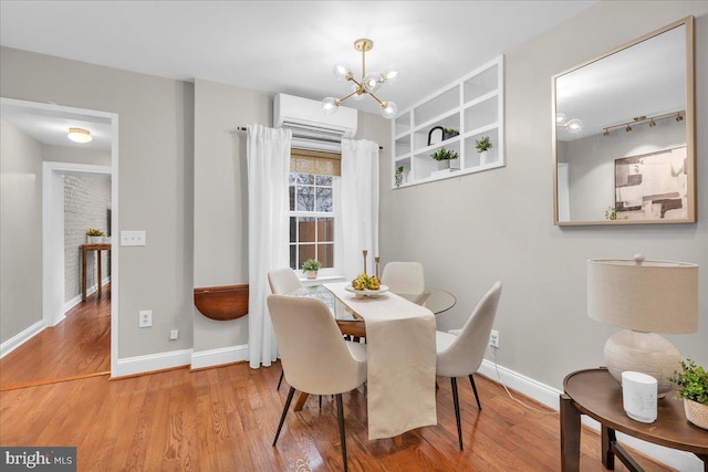 dining area with baseboards, a notable chandelier, a wall unit AC, and wood finished floors