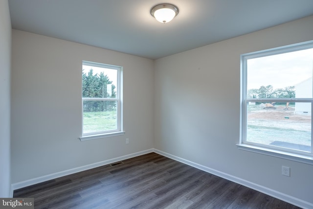 empty room with baseboards, dark wood finished floors, and visible vents