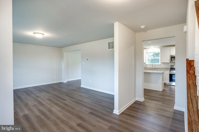 unfurnished room with dark wood finished floors, visible vents, and baseboards
