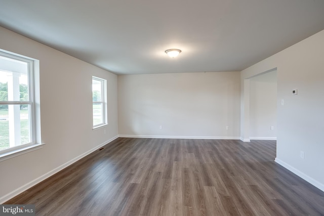 spare room with dark wood-style flooring and baseboards