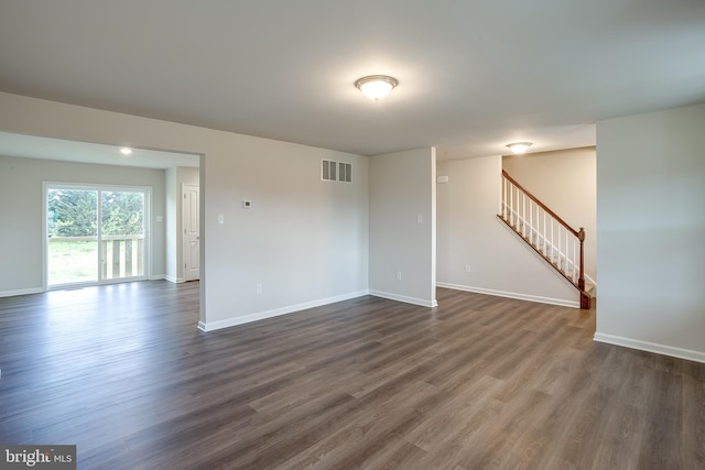 unfurnished living room with stairway, baseboards, dark wood-style floors, and visible vents