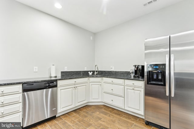 40999 Waxwing Dr, Leesburg, VA 20175 - kitchen with stainless steel appliances, a sink, white cabinets, dark stone counters, and light wood-type flooring