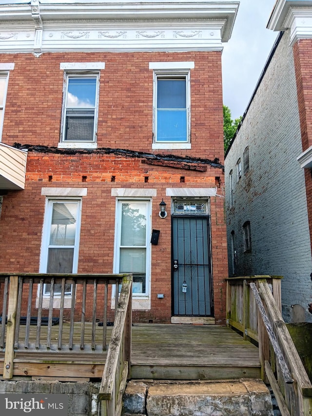 doorway to property with brick siding and a deck