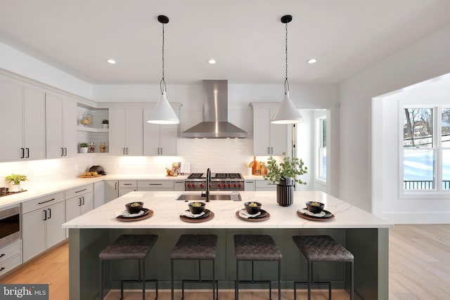kitchen with wall chimney exhaust hood, open shelves, a sink, decorative backsplash, and recessed lighting