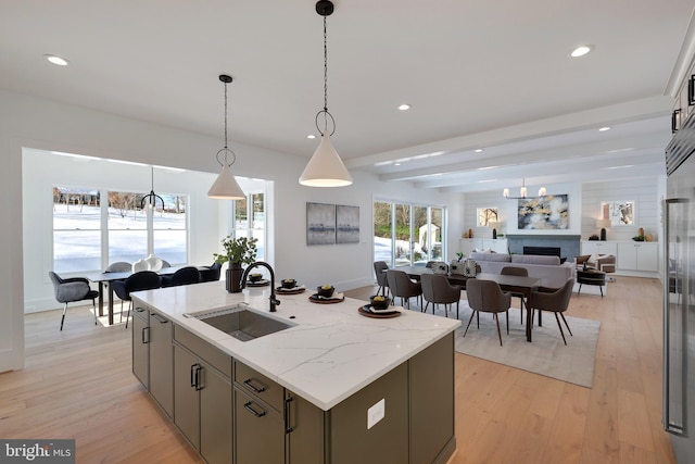 kitchen with a sink, recessed lighting, open floor plan, a fireplace, and light wood-style floors