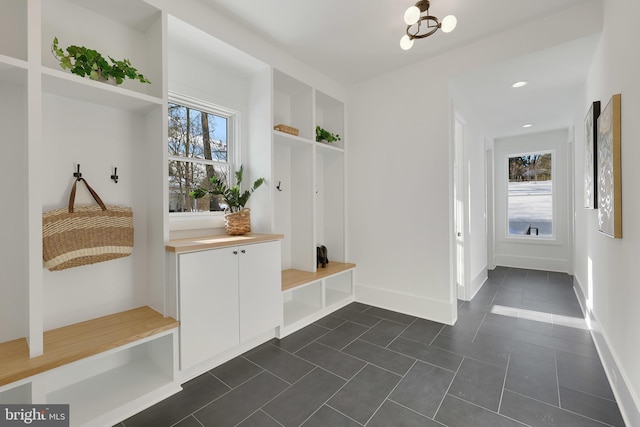 mudroom featuring dark tile patterned floors, baseboards, and a chandelier