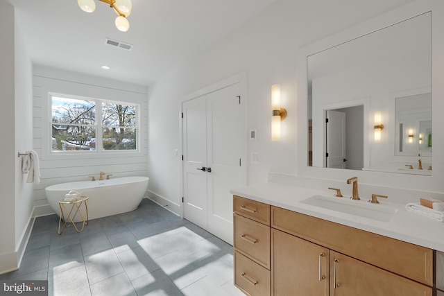 full bath featuring a soaking tub, vanity, tile patterned flooring, and baseboards