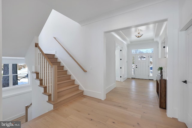 entrance foyer with light wood-style flooring, stairs, and baseboards