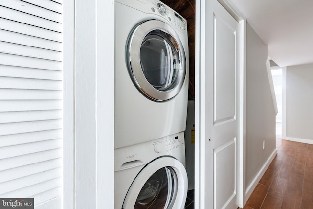 washroom featuring baseboards, laundry area, stacked washer / drying machine, and wood finished floors