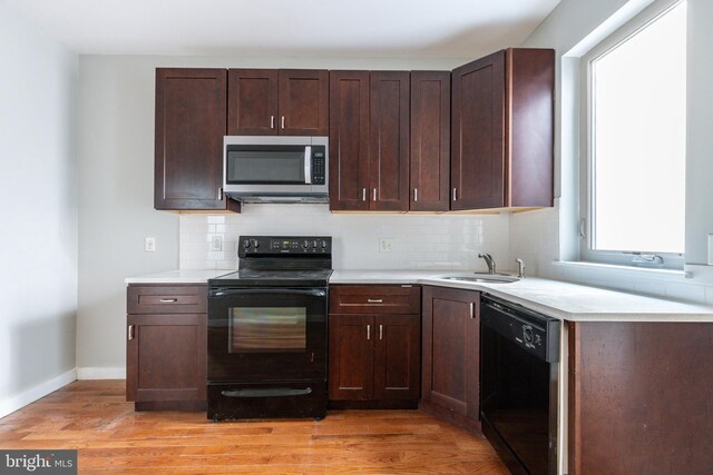 kitchen featuring black appliances, light wood finished floors, decorative backsplash, and a sink