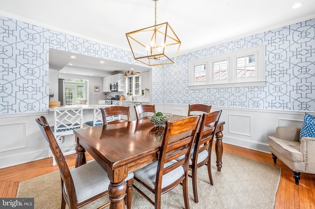 533 Park Ave, Towson, MD 21204 - dining space featuring wallpapered walls, a wainscoted wall, a chandelier, light wood-style flooring, and crown molding