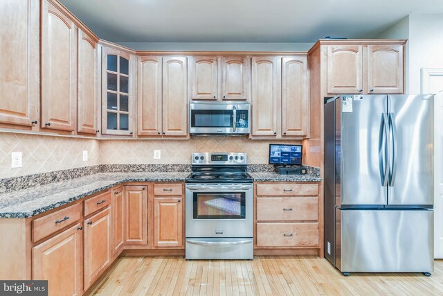 8200 Marshall Corner Rd, Pomfret, MD 20675 - kitchen featuring appliances with stainless steel finishes, light stone counters, glass insert cabinets, light brown cabinets, and light wood-style flooring