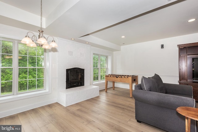 living area with a chandelier, baseboards, light wood finished floors, and a raised ceiling