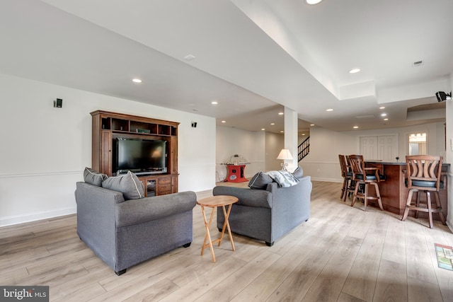 living area featuring light wood-style flooring, bar, stairs, recessed lighting, and baseboards