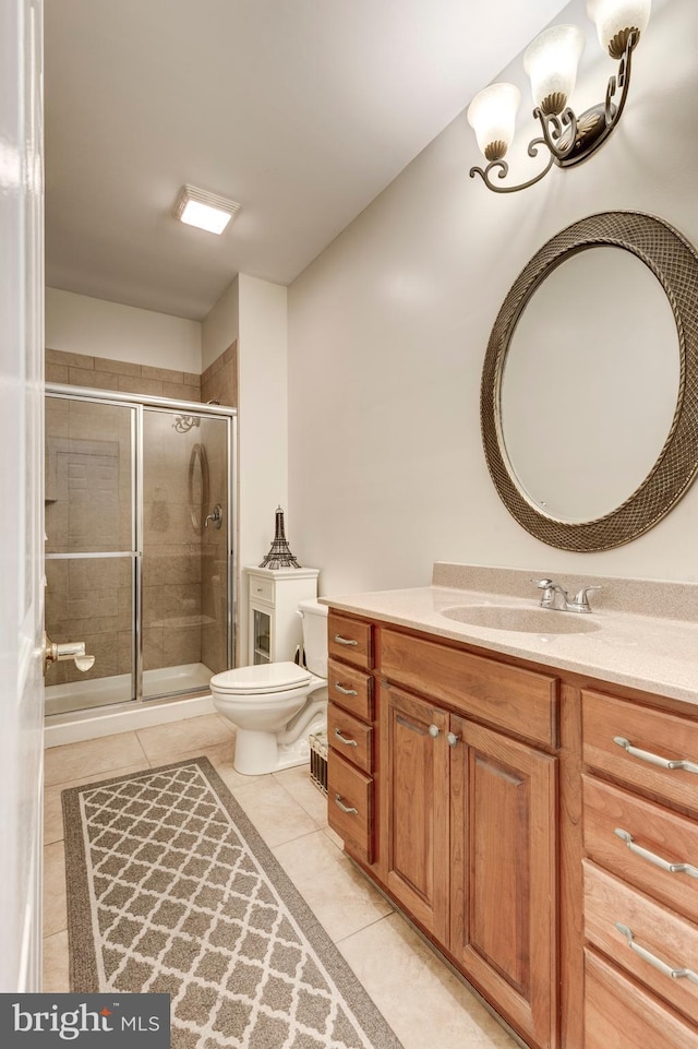 full bath featuring toilet, tile patterned flooring, vanity, and a stall shower