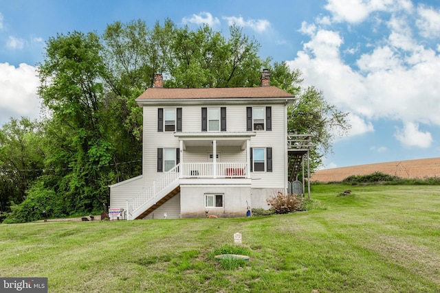 back of house featuring a lawn, stairway, and a chimney