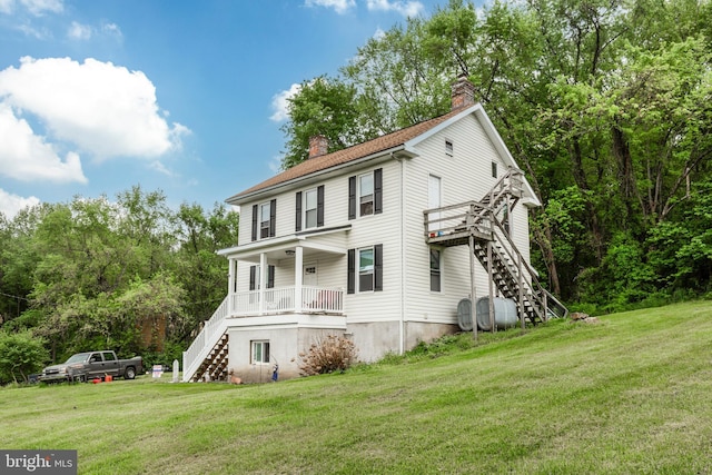 view of front of house with stairway, a chimney, and a front yard