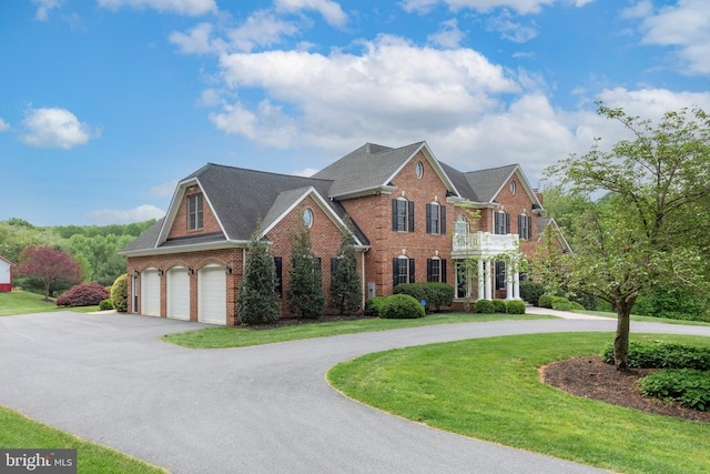 colonial home featuring curved driveway, brick siding, a garage, and a front yard
