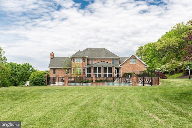 back of property with a sunroom, brick siding, a chimney, and a patio