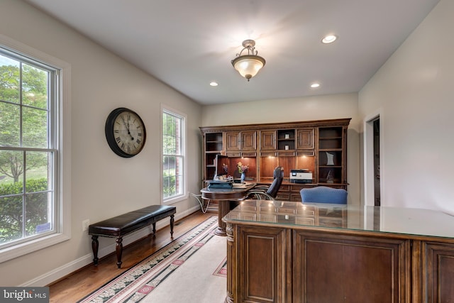 home office with healthy amount of natural light, baseboards, light wood-type flooring, recessed lighting, and built in desk