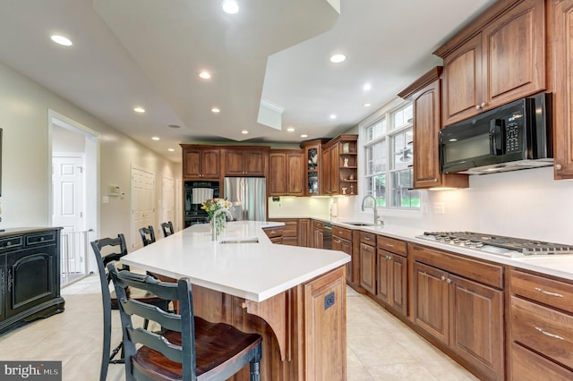 kitchen featuring black appliances, a sink, light tile patterned floors, a breakfast bar, and recessed lighting