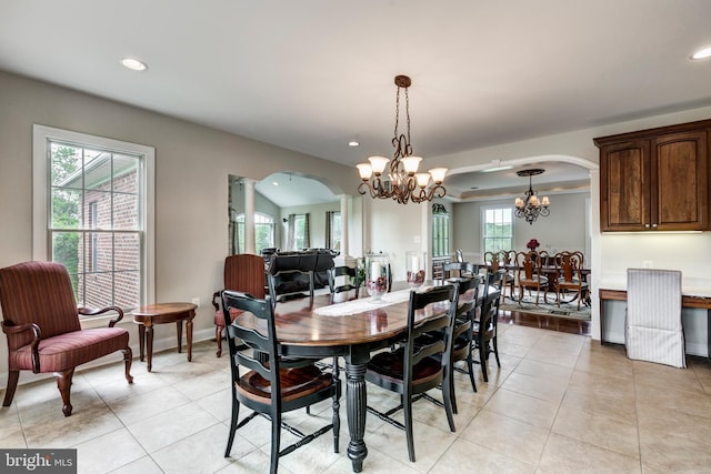dining area featuring arched walkways, a chandelier, recessed lighting, light tile patterned floors, and baseboards