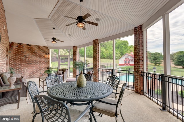 sunroom with ceiling fan, lofted ceiling, and outdoor dining space