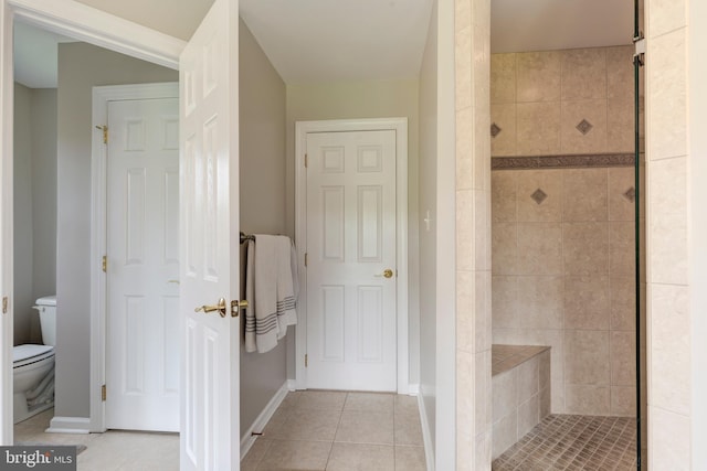 full bath with a shower stall, tile patterned floors, toilet, and baseboards