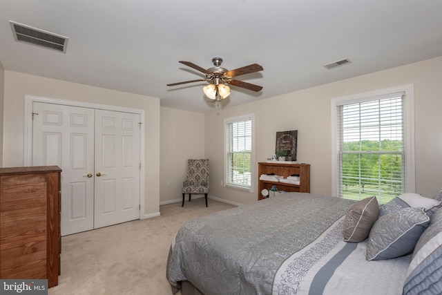 bedroom with light carpet, baseboards, a closet, and a ceiling fan