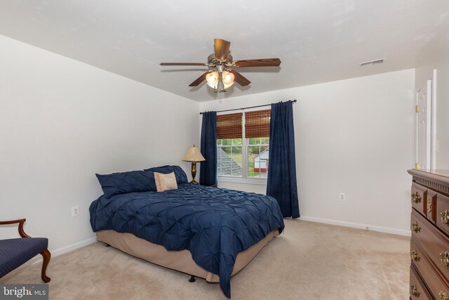 bedroom with light colored carpet, baseboards, and a ceiling fan
