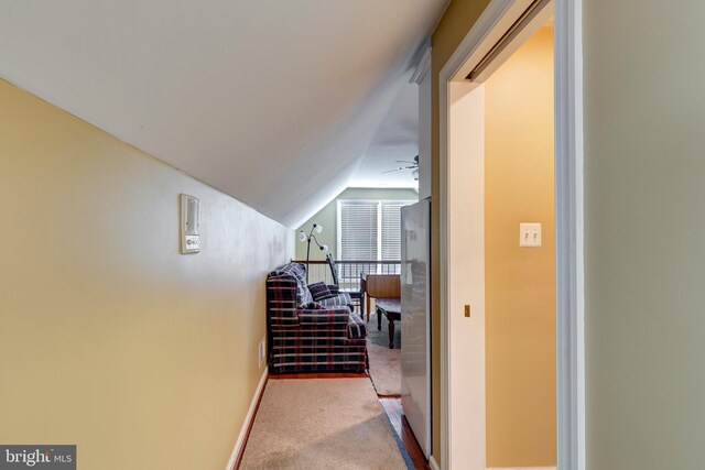 hallway featuring vaulted ceiling, carpet floors, and baseboards