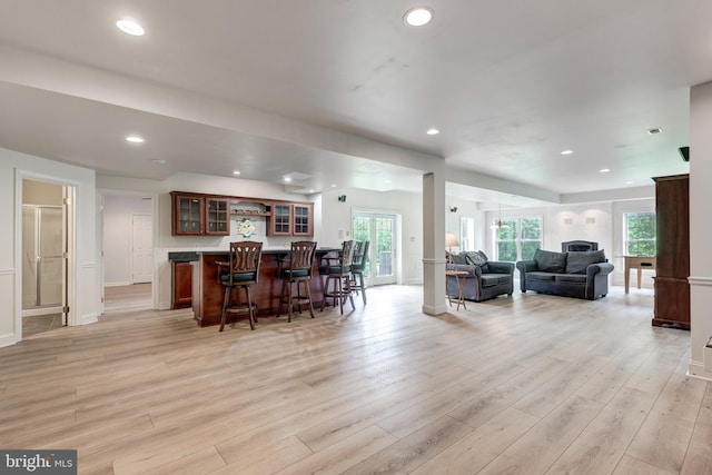 living room with bar area, light wood finished floors, recessed lighting, and baseboards
