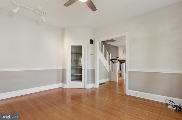 spare room with light wood finished floors, ceiling fan, visible vents, rail lighting, and stairway