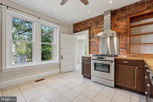 kitchen with visible vents, wall chimney exhaust hood, gas stove, light countertops, and a ceiling fan