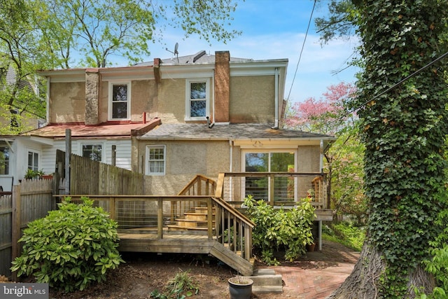 back of property featuring stucco siding, fence, and a wooden deck