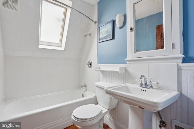 full bath featuring toilet, shower / bathing tub combination, wainscoting, and a skylight