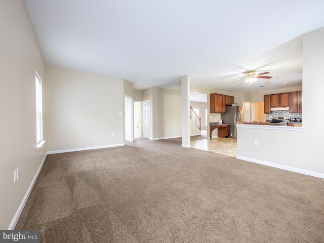 73 Marblehead Rd, Inwood, WV 25428 - unfurnished living room with light colored carpet, stairway, baseboards, and a ceiling fan