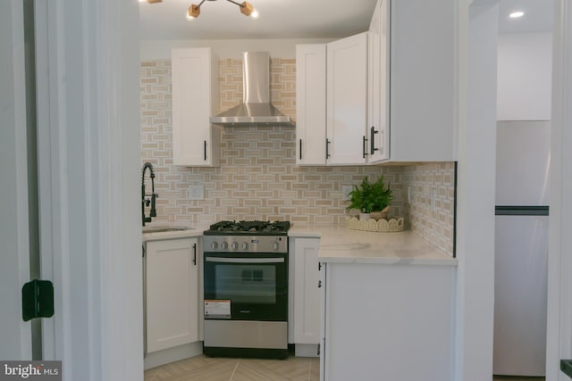 5446 Varnum St, Bladensburg, MD 20710 - kitchen with stainless steel range with gas stovetop, wall chimney exhaust hood, a sink, white cabinetry, and decorative backsplash