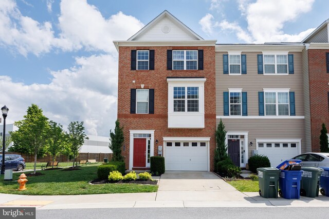 townhome / multi-family property featuring driveway, brick siding, an attached garage, and a front yard