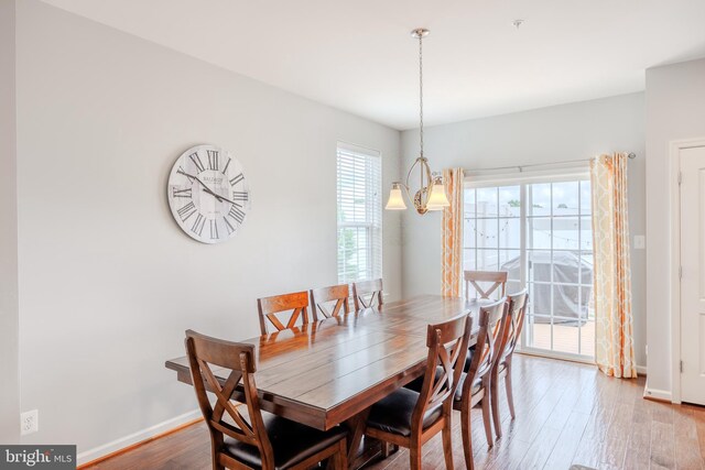 dining space featuring wood finished floors, baseboards, and a chandelier