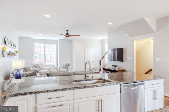 kitchen with a sink, dishwasher, open floor plan, light stone counters, and recessed lighting
