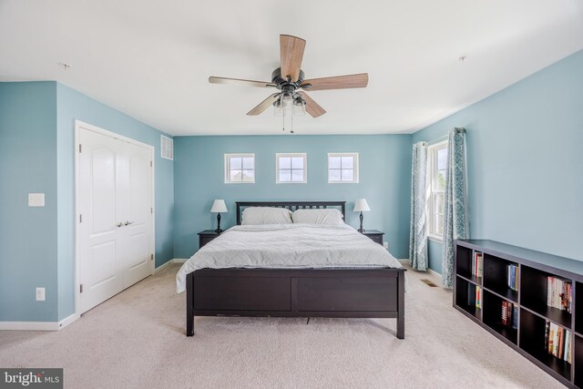 carpeted bedroom featuring multiple windows, baseboards, and ceiling fan