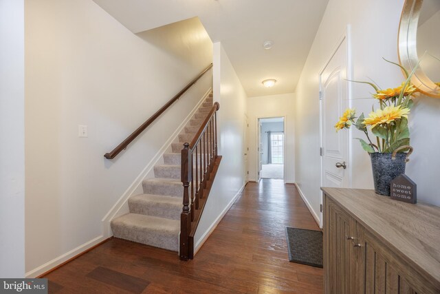 foyer with dark wood finished floors, stairs, and baseboards
