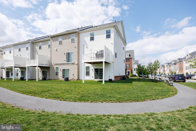 back of house featuring a residential view, a yard, and central air condition unit