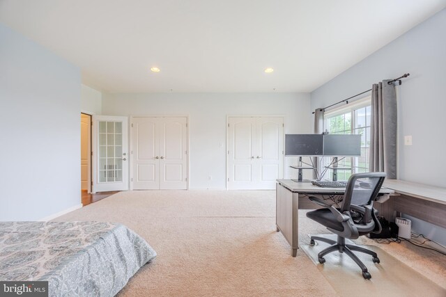 carpeted bedroom with a desk, recessed lighting, and two closets
